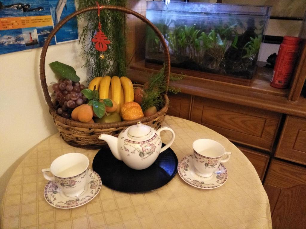 a table with two tea cups and a basket of fruit at 巧緣民宿11人包棟 in Hualien City