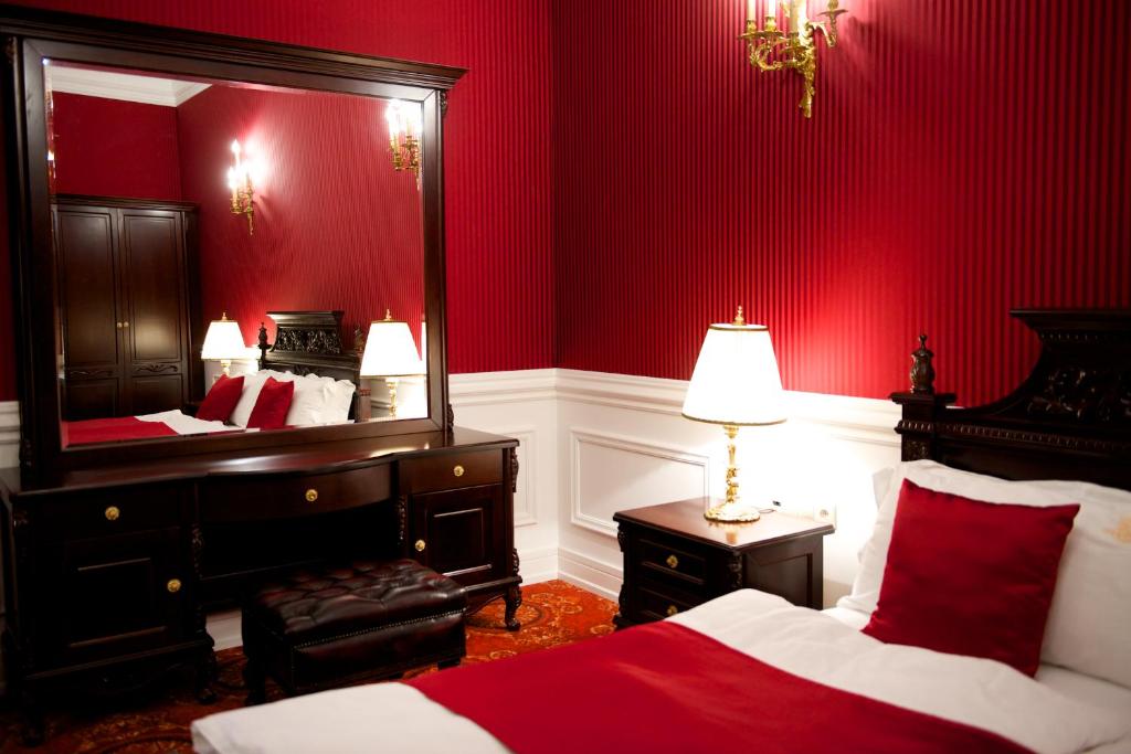 Dormitorio rojo con cama y espejo en Forgách Kastély, en Mándok