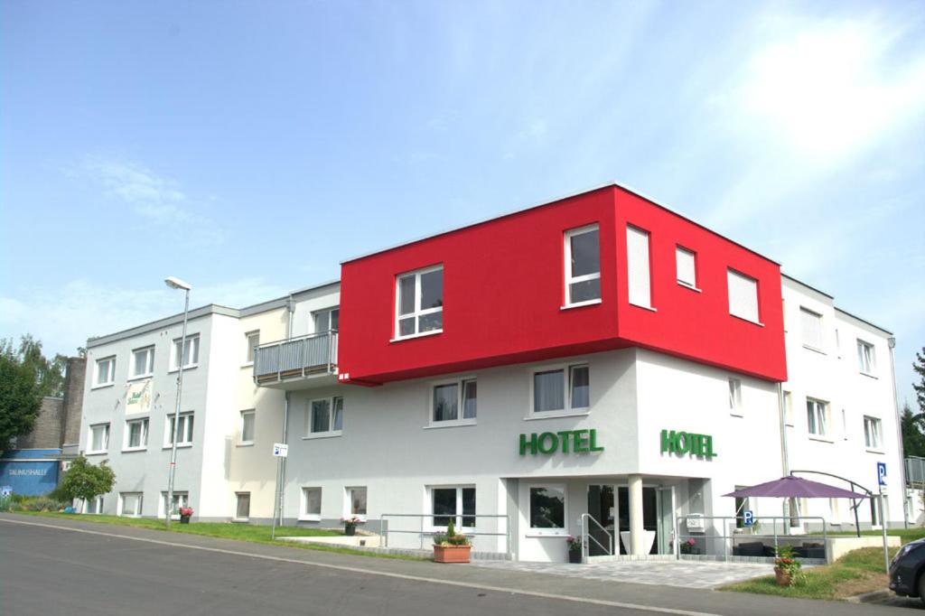 un hôtel blanc et rouge avec un toit rouge dans l'établissement Hotel Beuss, à Oberursel