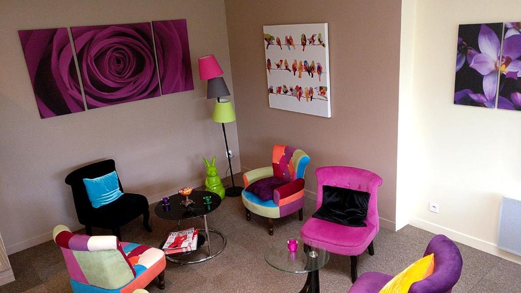 Lys Hôtel في Halluin: غرفة معيشة مع كراسي ملونة وطاولة