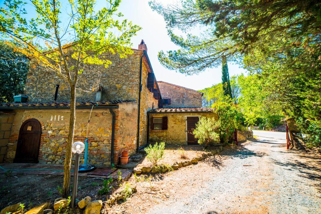 una antigua casa de piedra con entrada y árboles en Le Casette, en Guardistallo