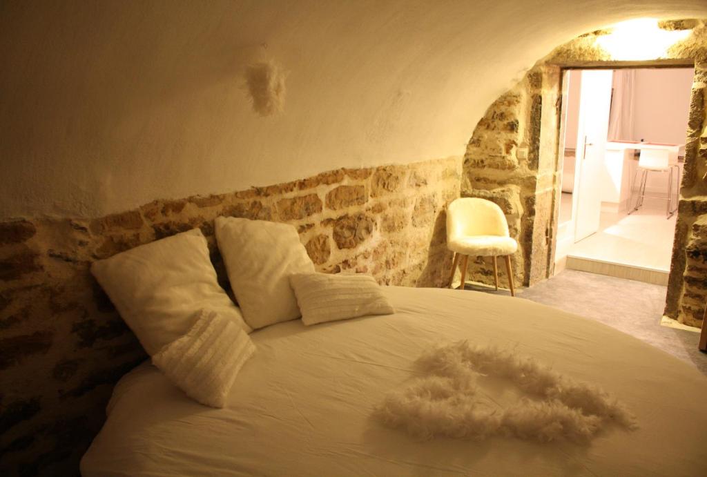 a bedroom with a white bed with a stone wall at Ly'Ove in Lyon