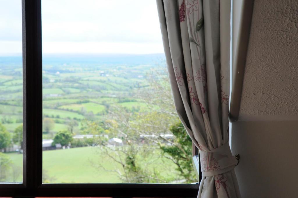 een raam met uitzicht op een groen veld bij Golden Hill Guest House in Omagh