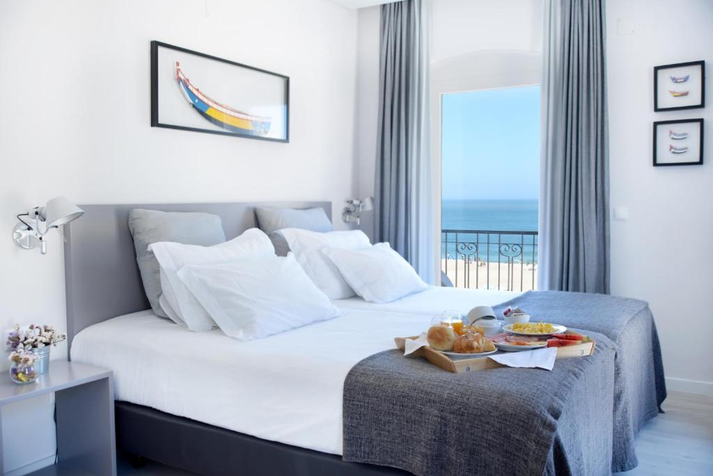 a hotel room with a bed with a tray of food on it at Hotel Mar Bravo in Nazaré