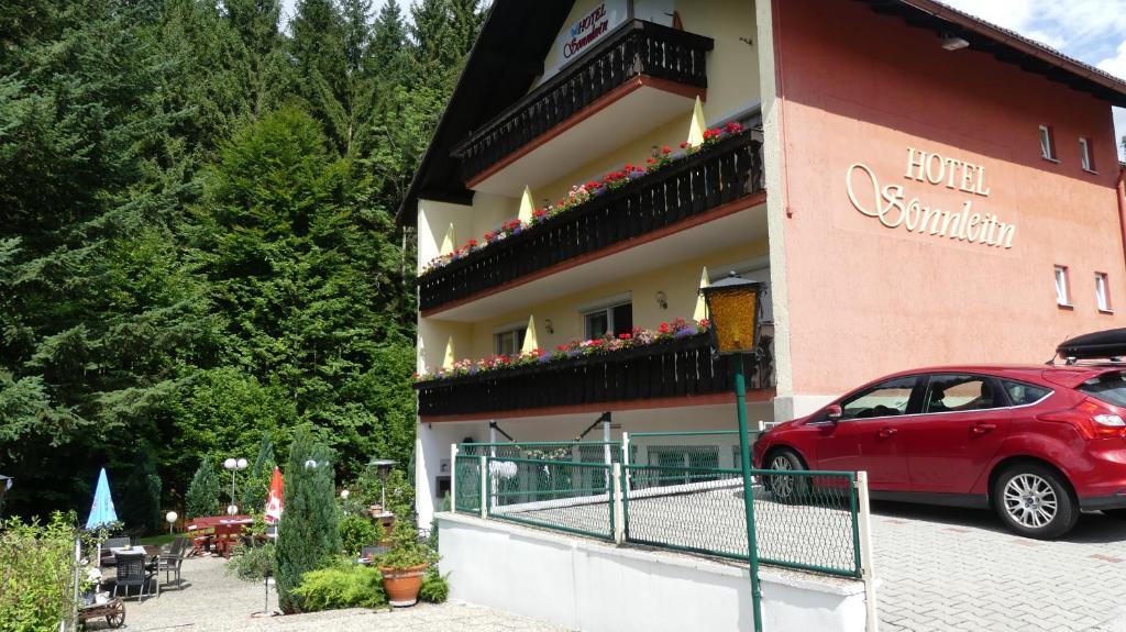 a red car parked in front of a building at Hotel Sonnleitn in Bodenmais