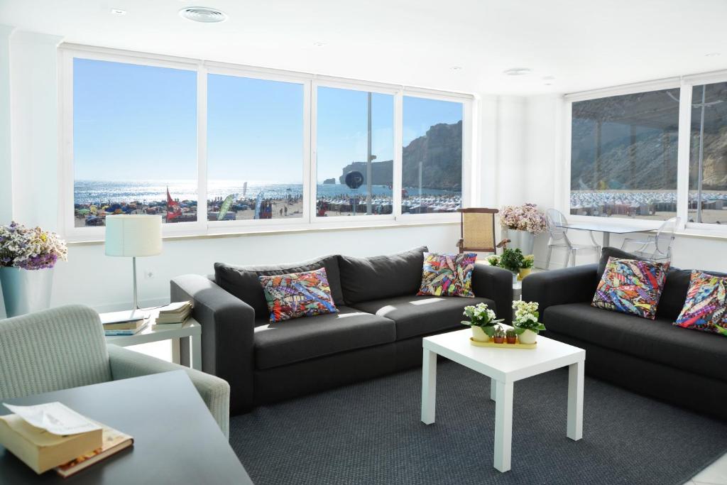 a living room with couches and a table and windows at Hotel Mar Bravo in Nazaré