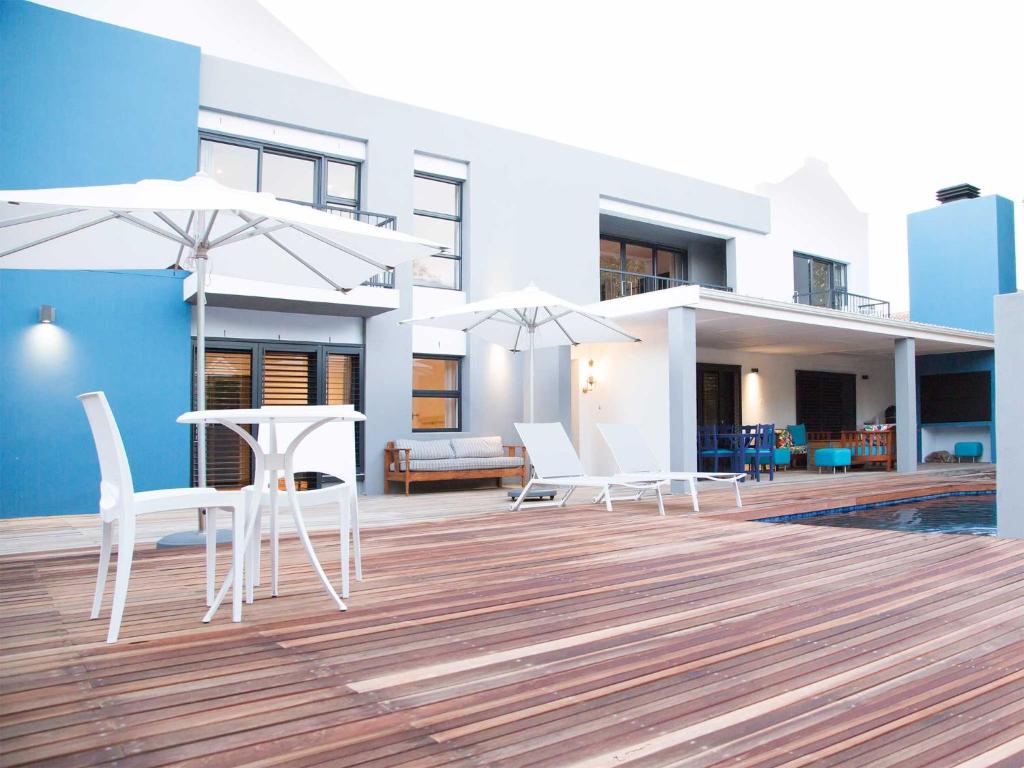 a patio with white chairs and tables and umbrellas at 7 Ackermann Place Guest House in Stellenbosch