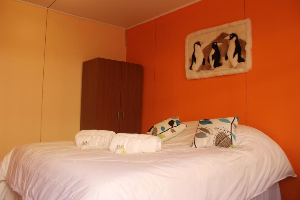 um quarto com uma cama branca e uma parede laranja em Hostal Baquedano em Puerto Natales