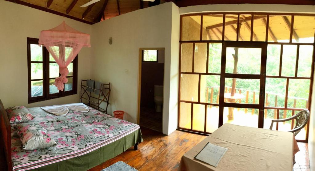 a bedroom with a bed in a room with windows at Seasons Four Mini Jungle Cabana in Matara