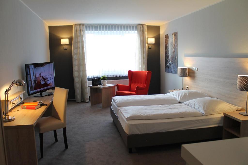 a hotel room with a bed and a desk at Hotel Westerfeld in Hemmingen