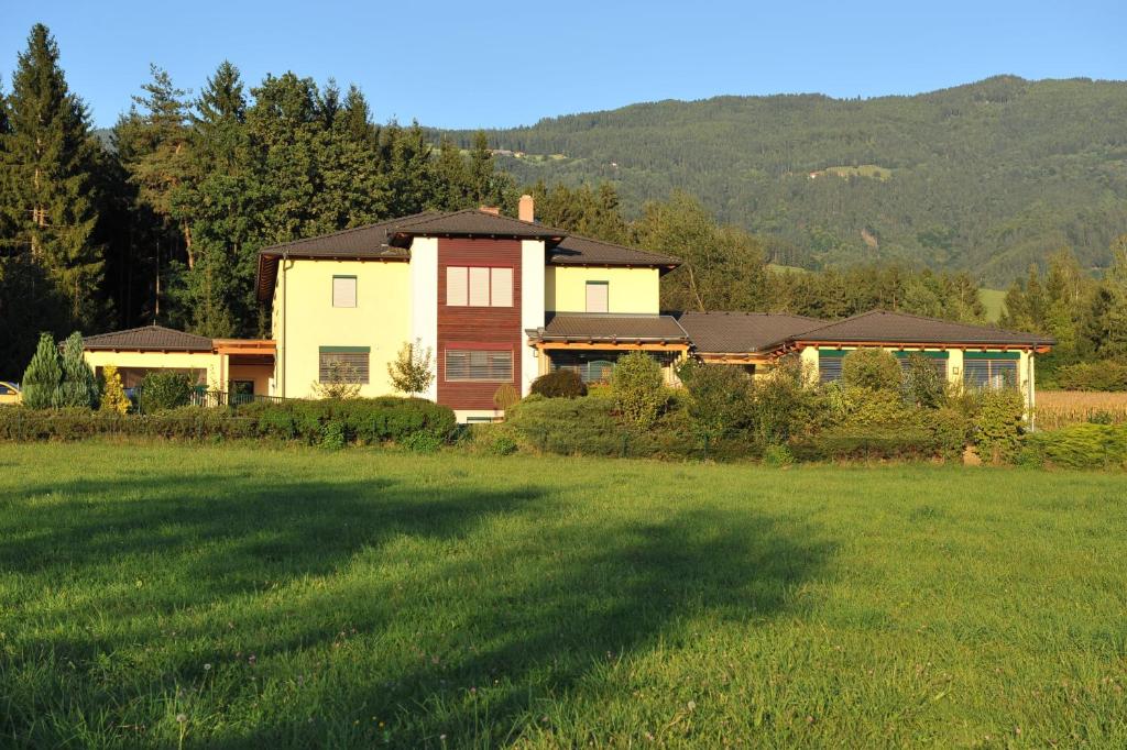 a house in the middle of a grass field at Wellness Pension Waldhof in Sankt Georgen