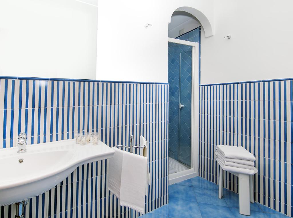 a bathroom with a white sink and blue tiles at Hotel Pupetto in Positano
