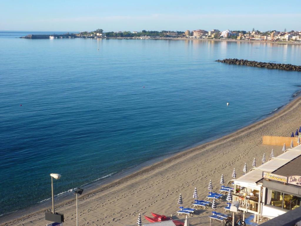 a beach with chairs and umbrellas next to the water at Hotel Palladio in Giardini Naxos