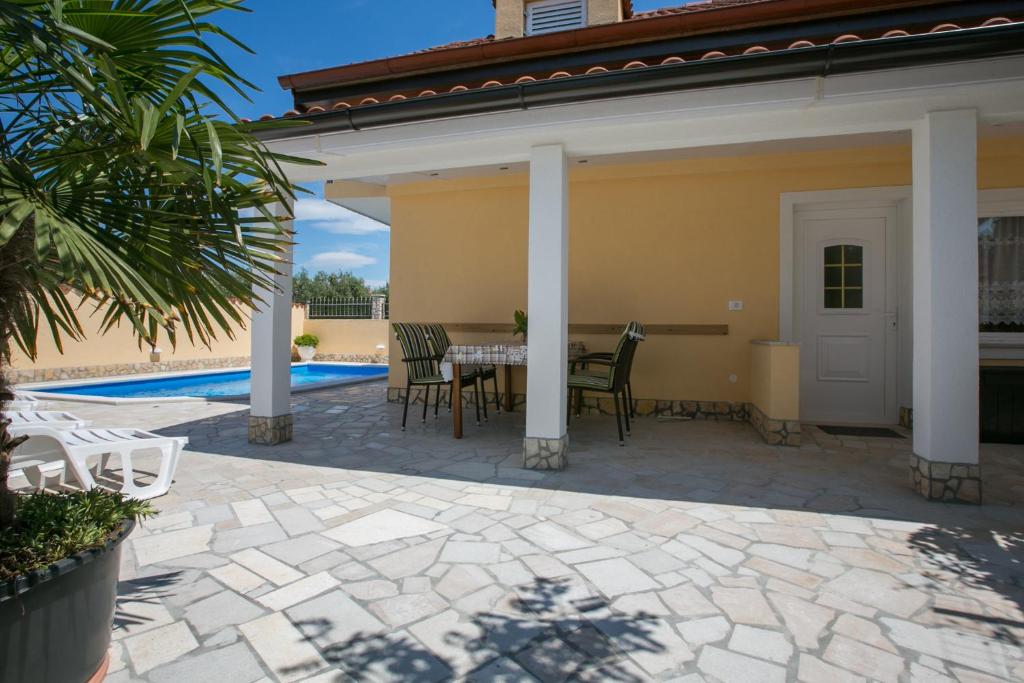 taras ze stołem i krzesłami obok basenu w obiekcie Holiday Home "Mala kuća " with heated pool w Puli