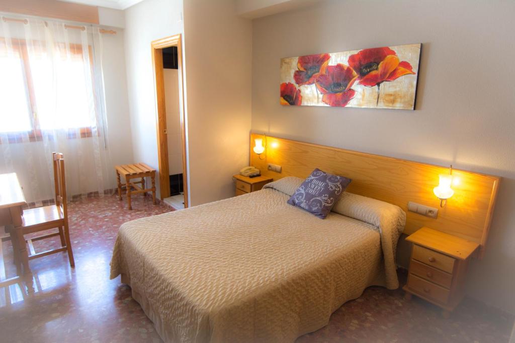 L'Oncle Pere Habitacions في L'Alcúdia: غرفة نوم بسرير وطاولة مع كرسي