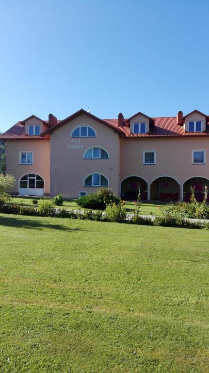 a large building with a green field in front of it at Pokoje Pod Łukami in Solina