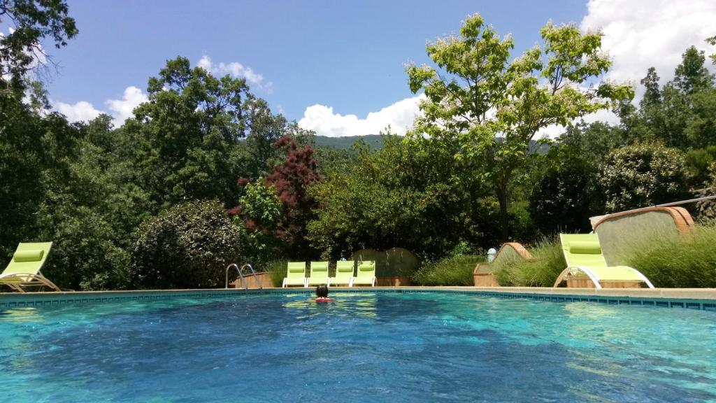 einen Pool mit Stühlen und eine Person im Wasser in der Unterkunft Hotel Rural El Camino in Candeleda