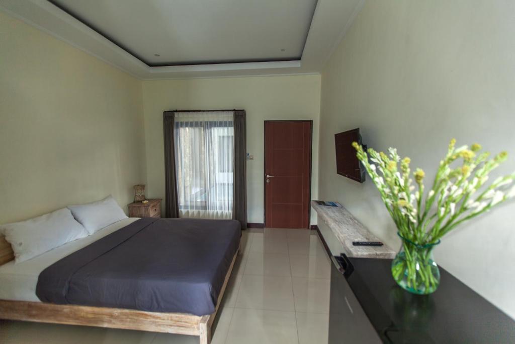 um quarto com uma cama e um vaso de flores em Umah Bagus em Sanur