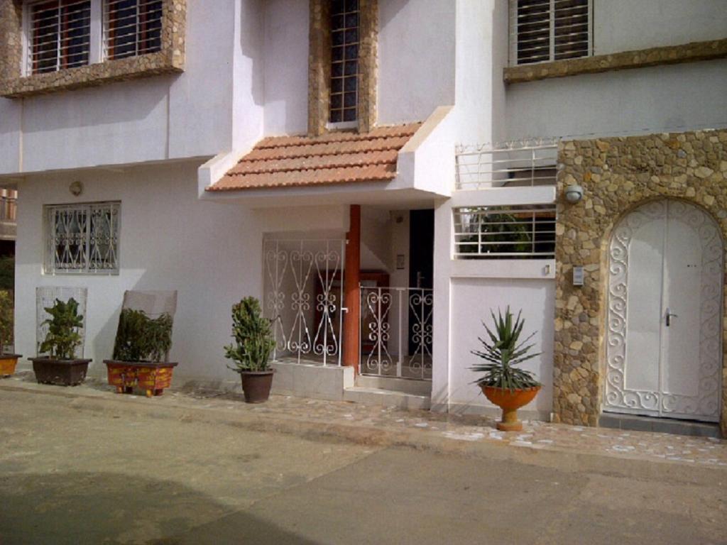 Biały dom z doniczkami przed nim w obiekcie Appartements F2 & F3 à louer Ouest-Foire Dakar w mieście Dakar