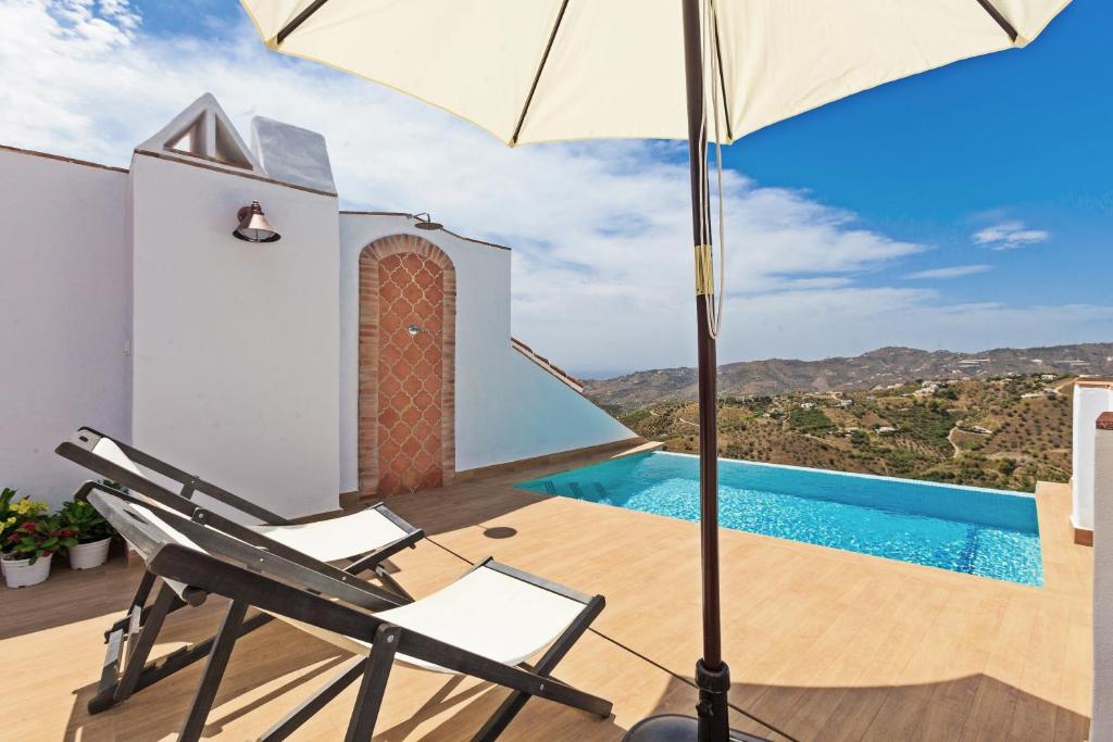 夫里希利亞納的住宿－EL TORREON 109 CHARMING B&B - Recomendado Adultos，一个带椅子和遮阳伞的庭院和一个游泳池