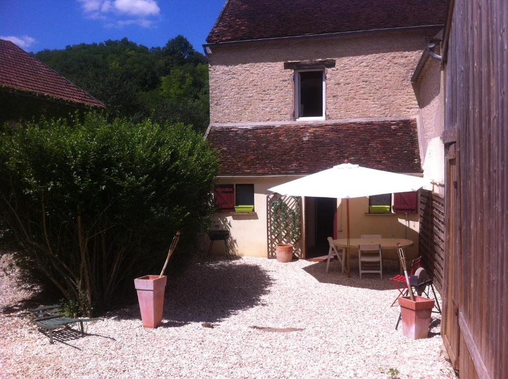 une terrasse avec une table et un parasol en face d'un bâtiment dans l'établissement Gite Vezelay, à Chamoux