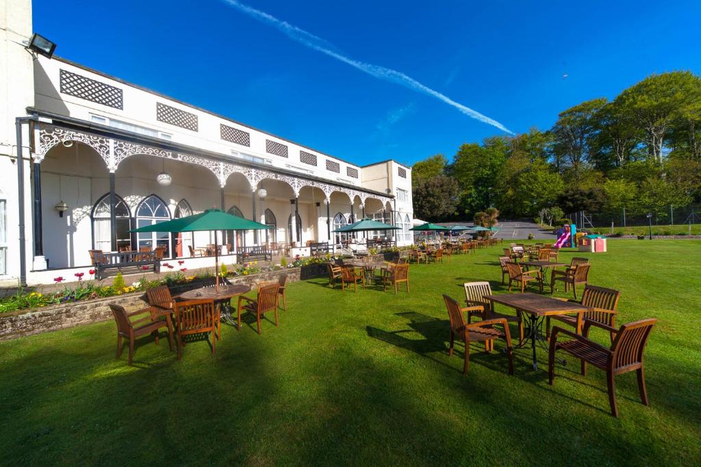 eine Außenterrasse mit Tischen und Stühlen sowie ein Gebäude in der Unterkunft Langstone Cliff Hotel in Dawlish