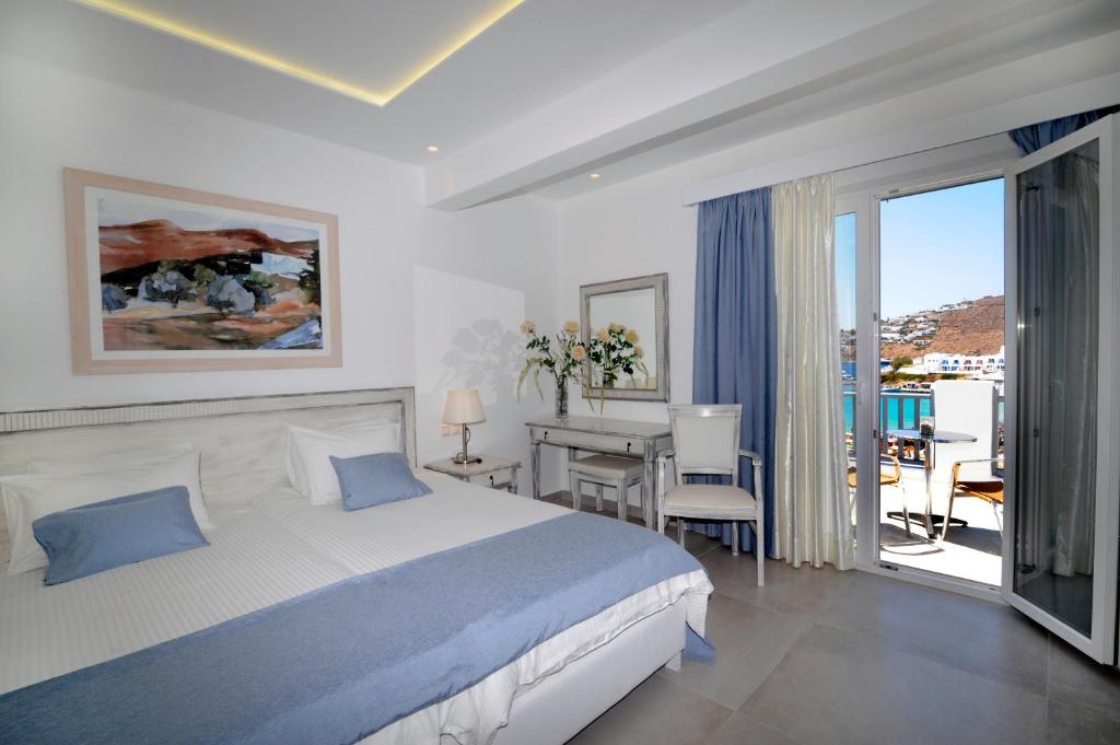a bedroom with a bed and a desk and a balcony at Hotel Anna in Platis Yialos Mykonos