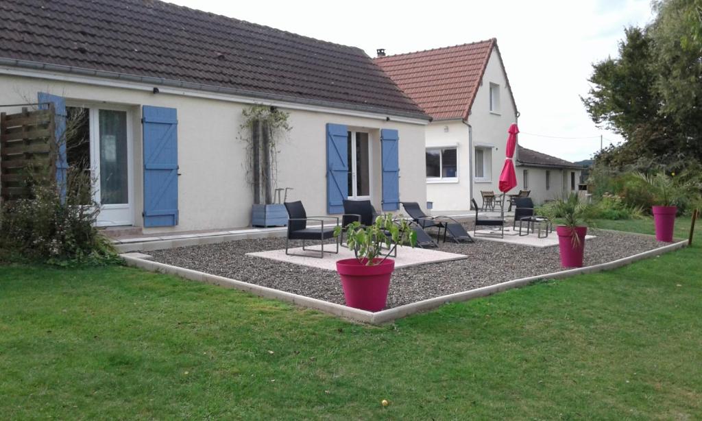 a yard with chairs and potted plants in front of a house at Chambre d'hotes Le Hamel in Le Hamel