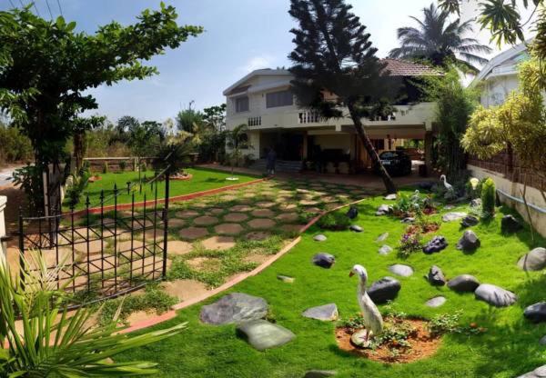 um quintal com pássaros na relva em frente a uma casa em Urban Retreat Homestay em Mangalore