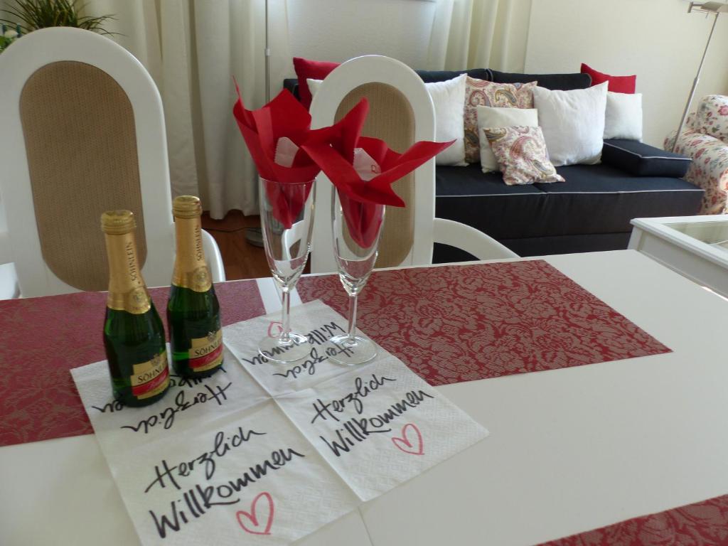 uma mesa com duas garrafas de champanhe e flores vermelhas em FeWo Parkblick mit 2 Bädern em Bad Harzburg