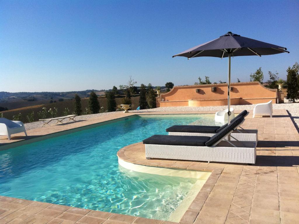 a swimming pool with an umbrella and a chair at Relais Il Margarito in Montefano