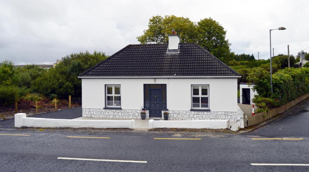 uma casa branca com um telhado preto numa rua em Ash Tree Cottage em Bangor