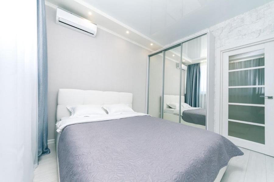 a white bedroom with a bed and a mirror at Apartment on Draghomanova 2a in Kyiv