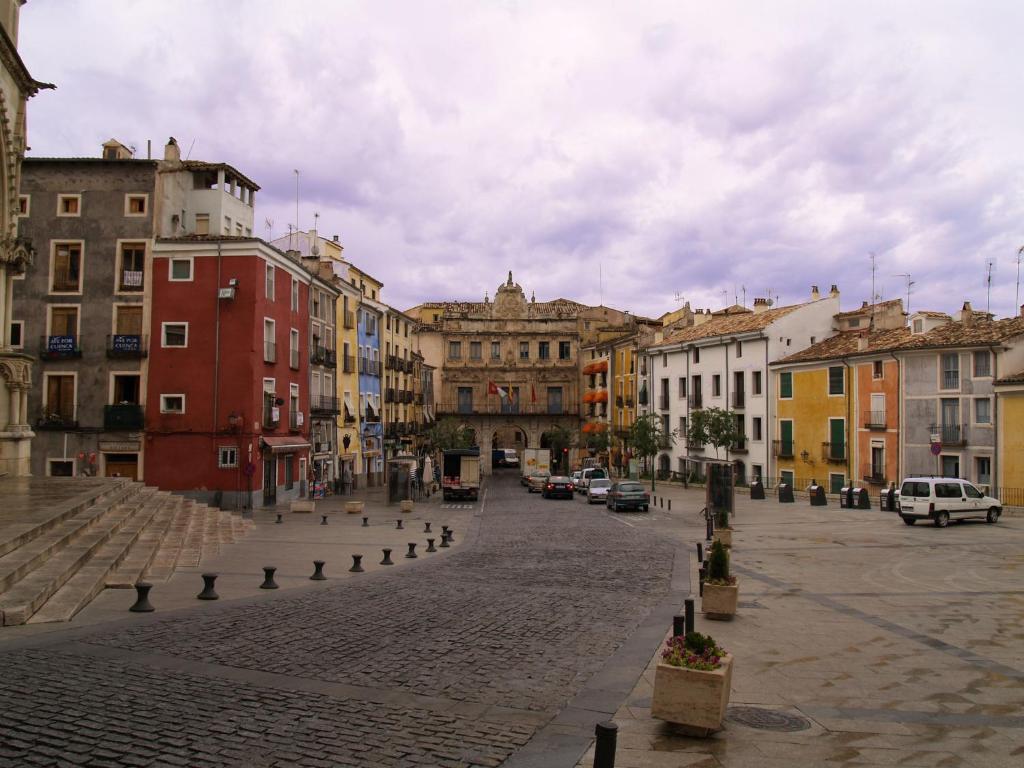a city street with buildings and cars on a cloudy day at Ático en la Plaza Mayor in Cuenca
