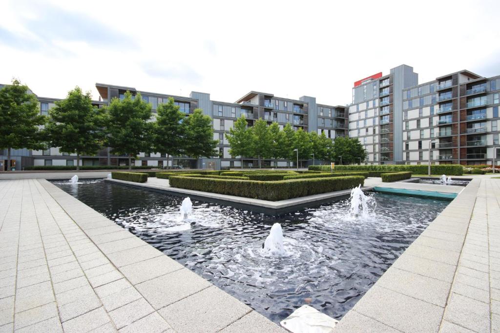 ミルトン・キーンズにあるiStay Apartments Vizionの背景の建物が立ち並ぶ公園の噴水
