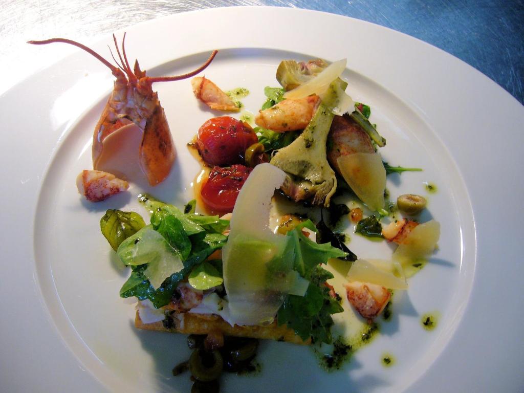 a white plate of food with a salad on it at Hotel Re'ser Stuff in Roeser