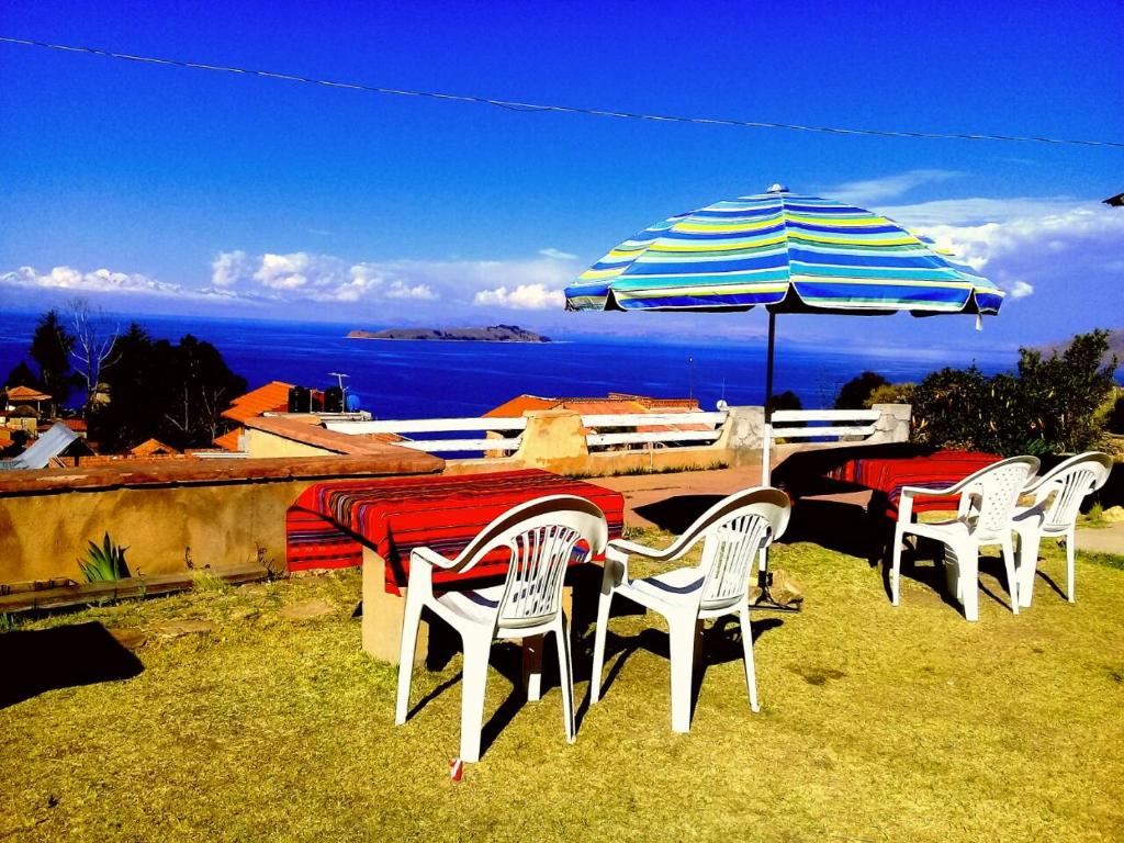 Hostal Tawri في Isla de Sol: مجموعة طاولات وكراسي مع مظلة