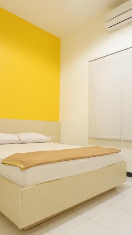 um quarto com uma cama grande e uma parede amarela em Pink House em Probolinggo