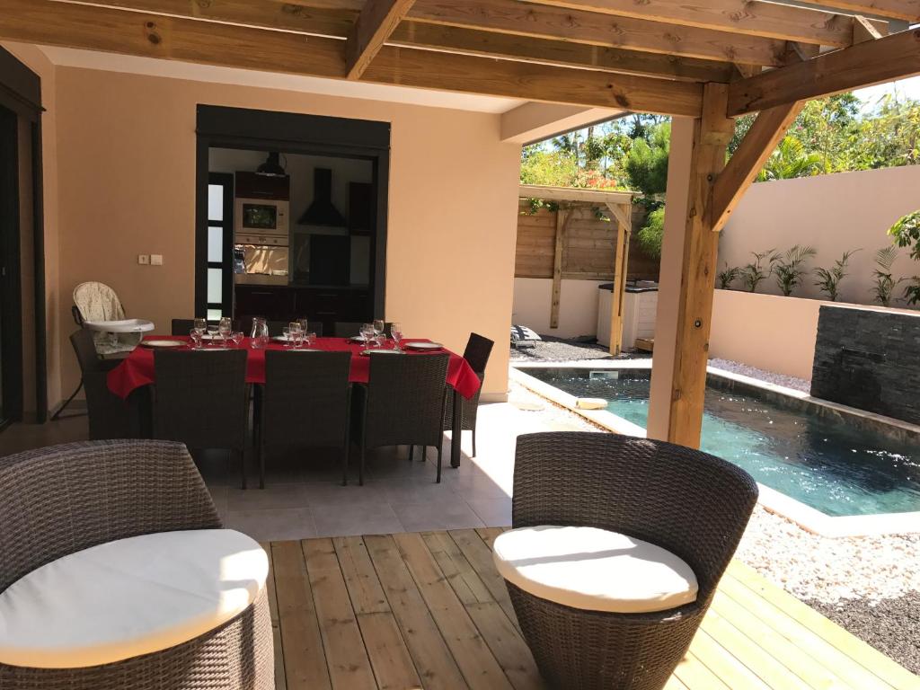 un patio con mesa y sillas y una piscina en Villa "Les porcelaines", en La Saline-Les-Bains