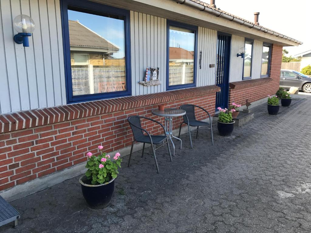 a patio with chairs and a table and some plants at Birkevej Rooms in Skagen