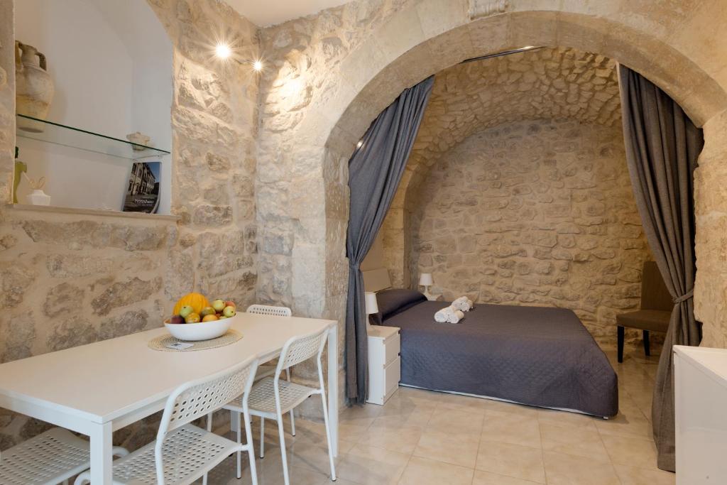 een slaapkamer met een bed en een tafel en stoelen bij Dammuso delle Gioie in Scicli