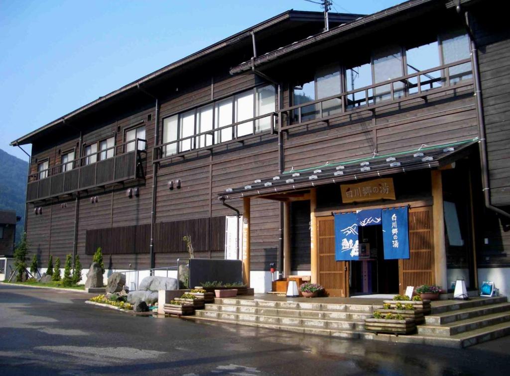 un edificio con una señal delante de él en 天然温泉白川郷の湯 en Shirakawa
