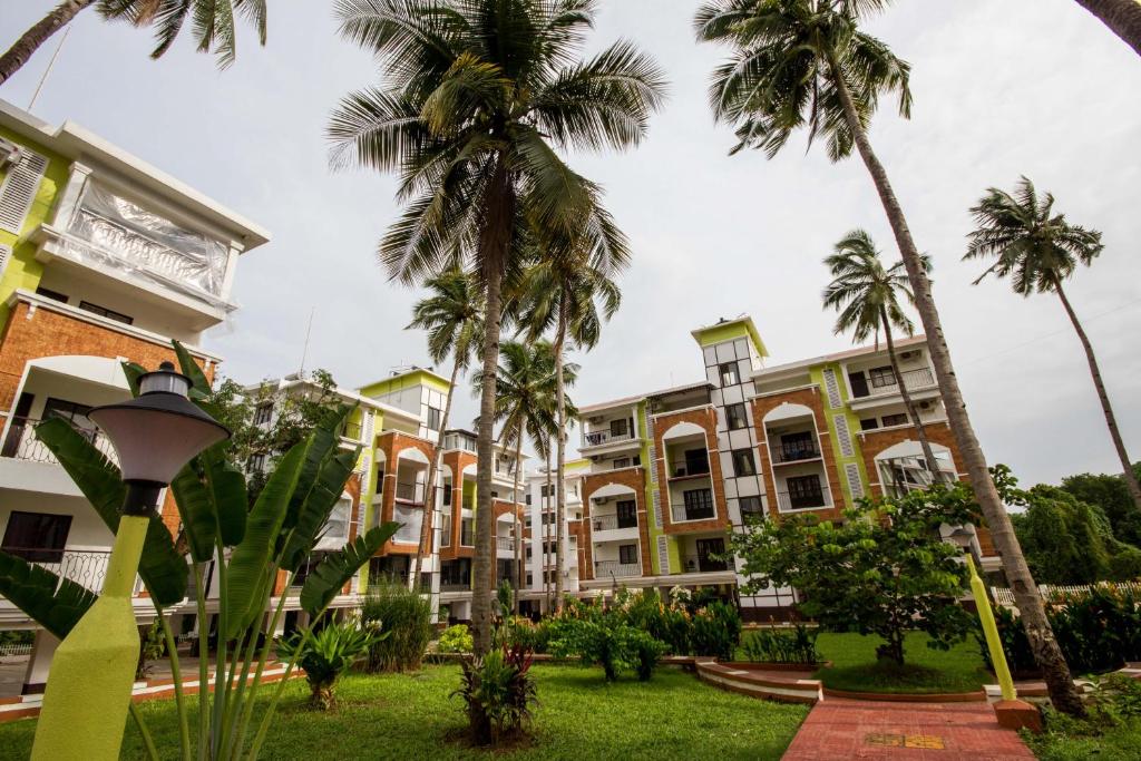 a row of palm trees in front of a building at Monarch Palms- Serviced Apartments (Managed by HNH Homes) in Candolim