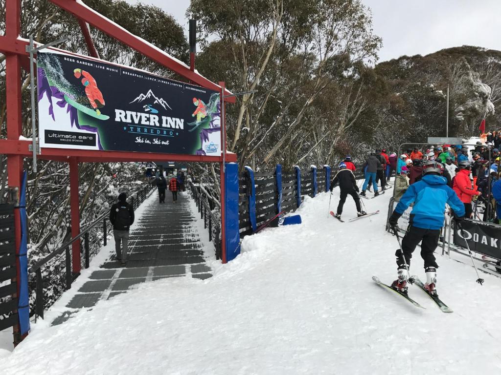 a group of people skiing down a snow covered slope at The River Inn Thredbo in Thredbo