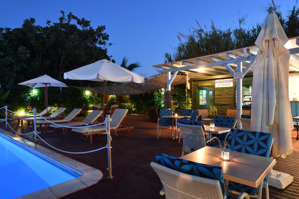 un patio con mesas y sombrillas junto a una piscina en Villa Katerina, en Parikia