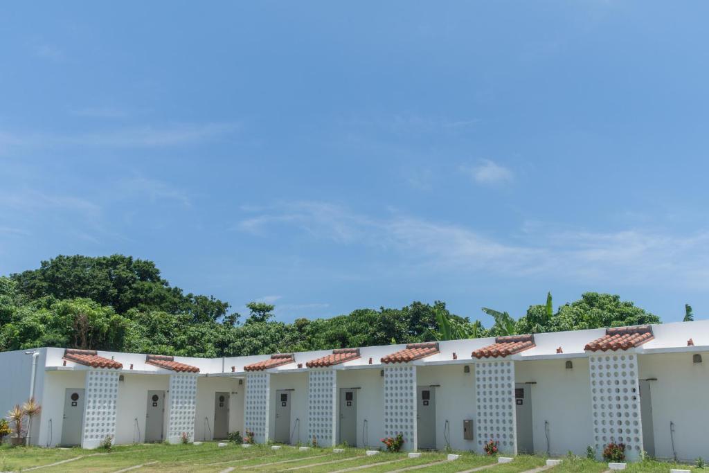 een rij witte gebouwen met bomen op de achtergrond bij Nata Beach Villa in Ishigaki Island