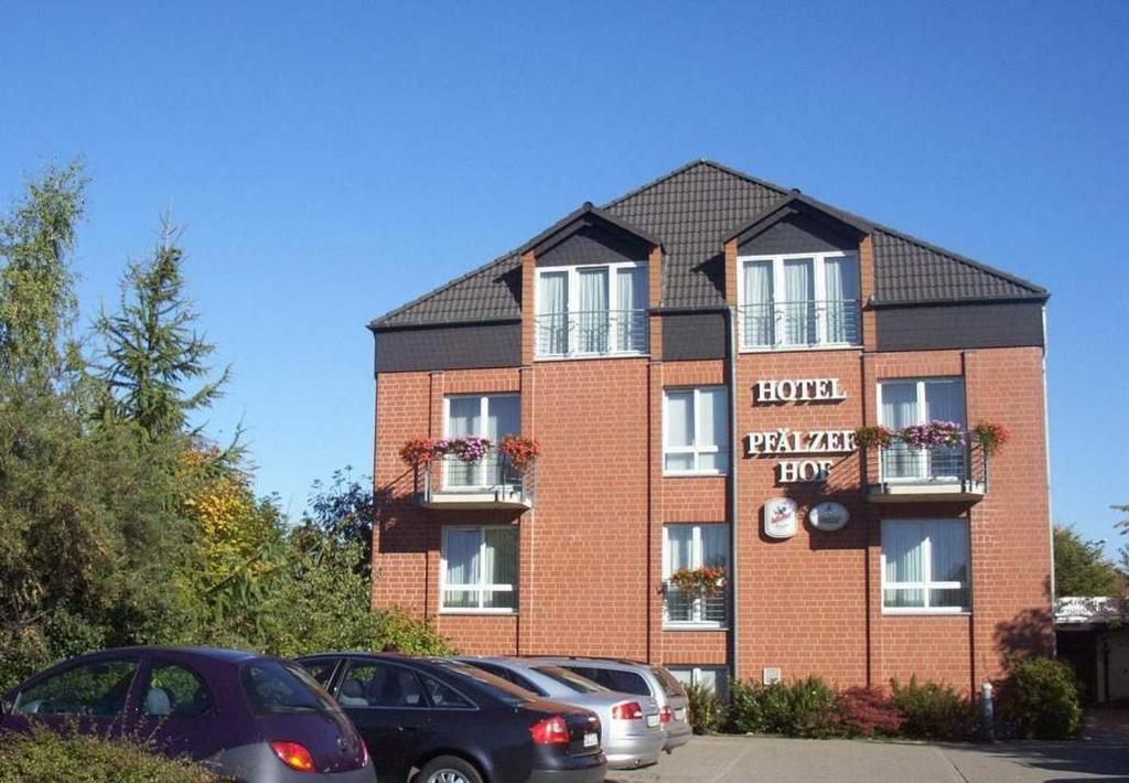 un edificio de ladrillo con coches estacionados frente a él en Hotel Pfälzer Hof en Brunswick