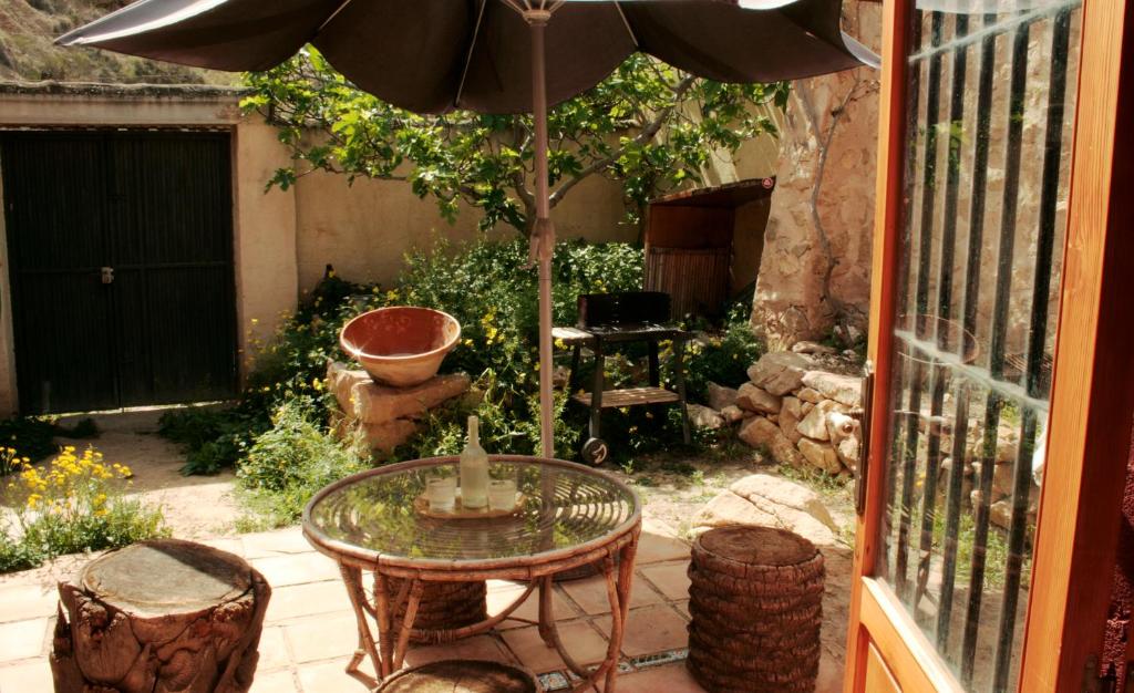 eine Terrasse mit einem Tisch, einem Sonnenschirm und Stühlen in der Unterkunft Casica de Perintín Cottage in Ricote