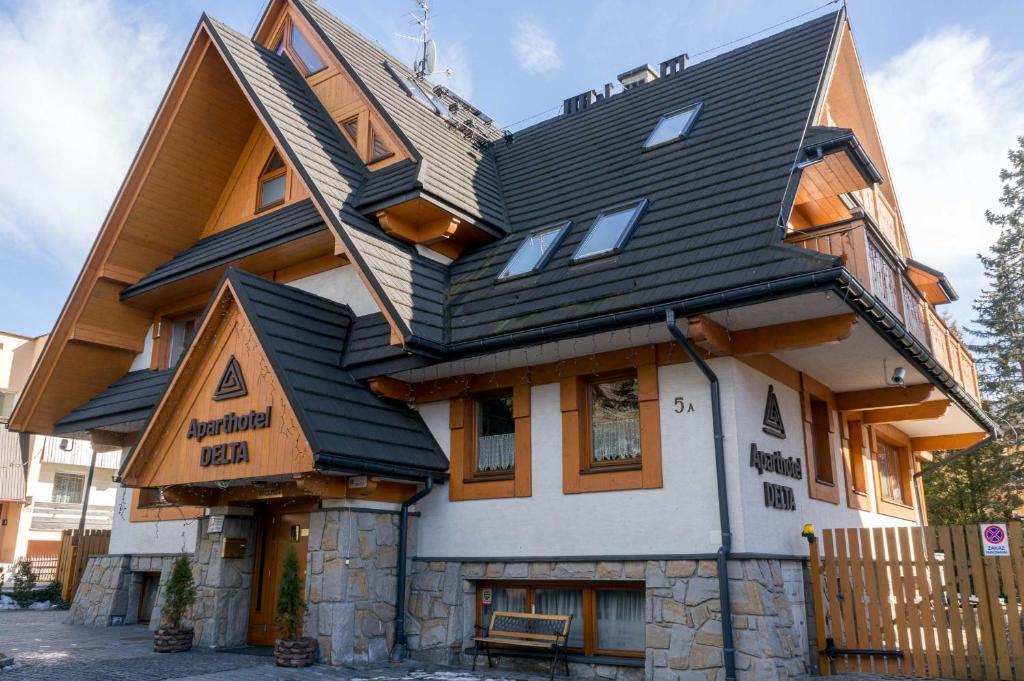 una casa con techo de gambrel encima en Aparthotel Delta Zakopane, en Zakopane