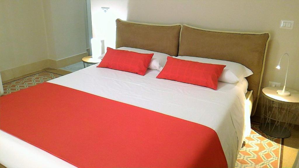 a red and white bed with two red pillows on it at Casa Isabela luxury rooms in Melfi
